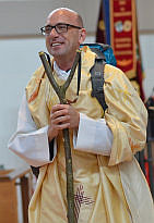 Pfarrer Moderegger bei der Amtseinführung mit Rucksack und Wanderstab