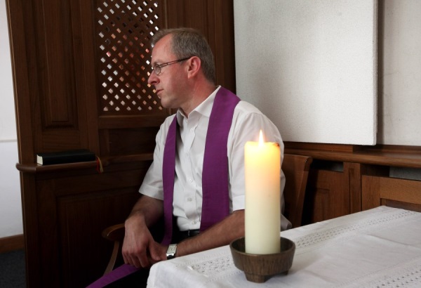 Priester im offenen Beichstuhl