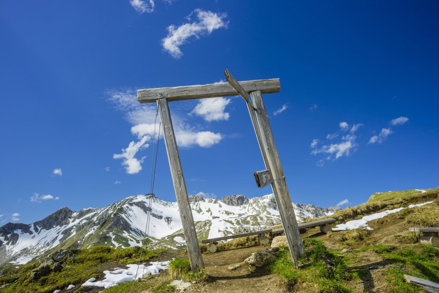 hölzerner Türrahmen vor sonnigem Alpenpanorama