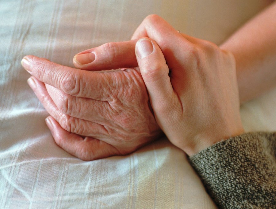 ein alter Mensch bekommt die Hand im Bett gehalten