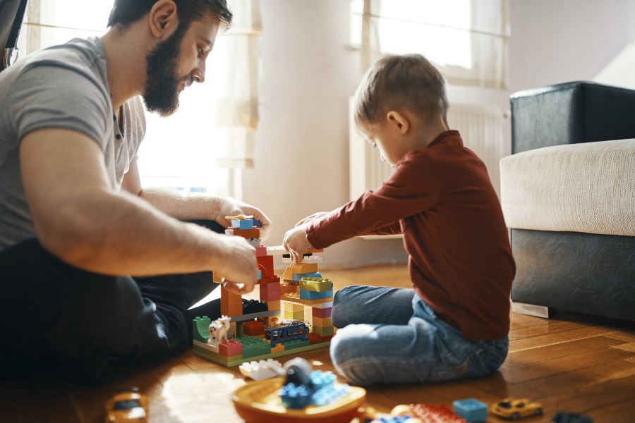 vater und sohn spielen mit lego im wohnzimmer