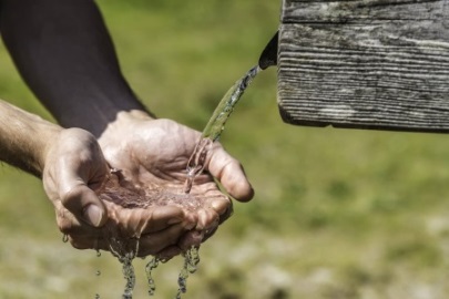 Hände fangen Wasser auf.