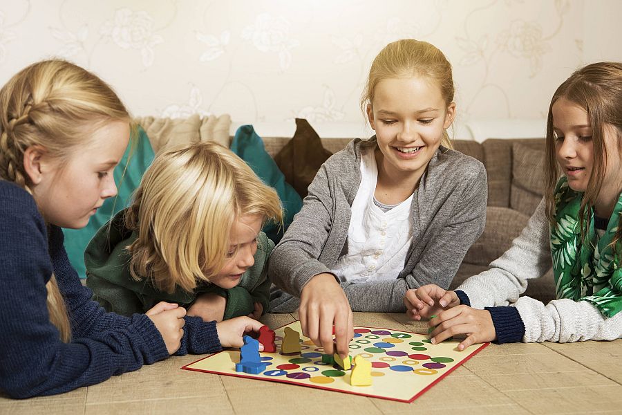 Vier Kinder spielen zusammen ein Brettspiel