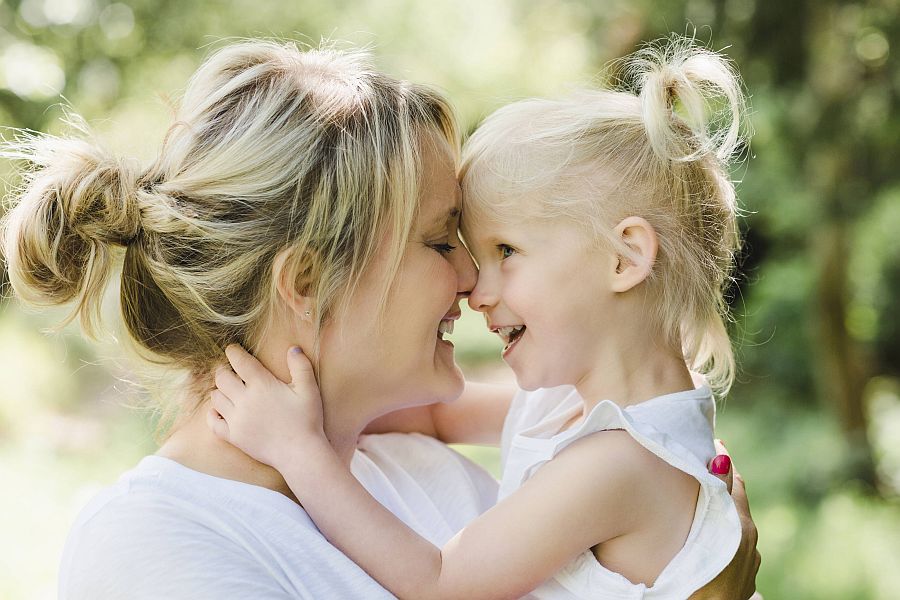 Mutter und kleines Mädchen umarmen sich liebevoll und stupsen ihre Nasen aneinander