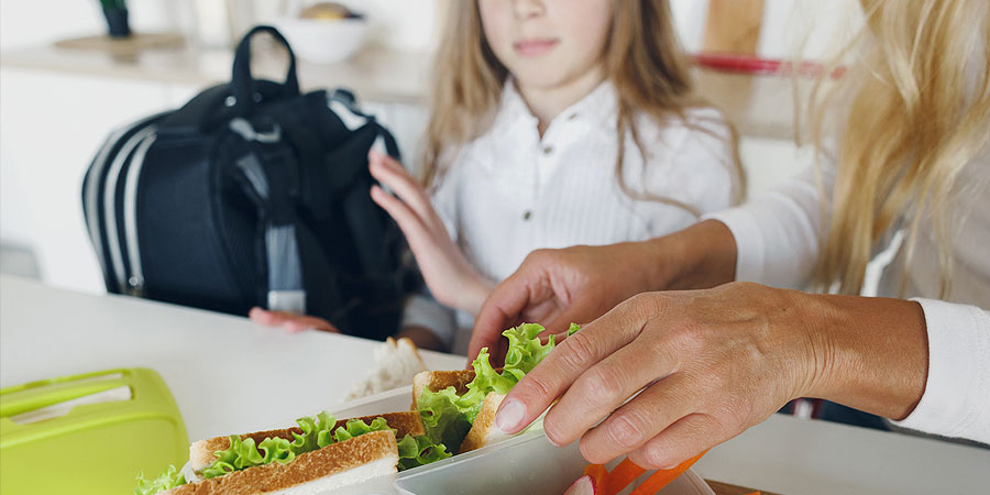 mutter richtet brotzeit für kind her