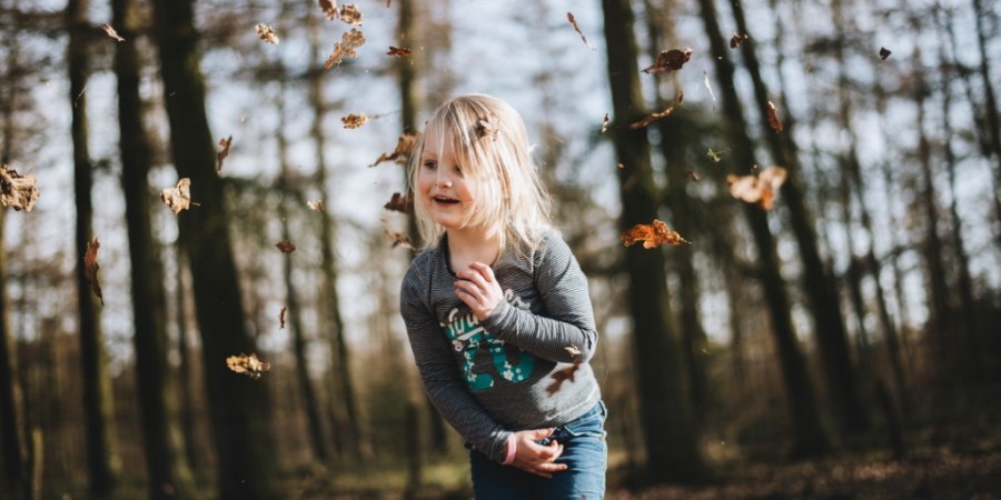 Mädchen spielt mit Herbstlaub