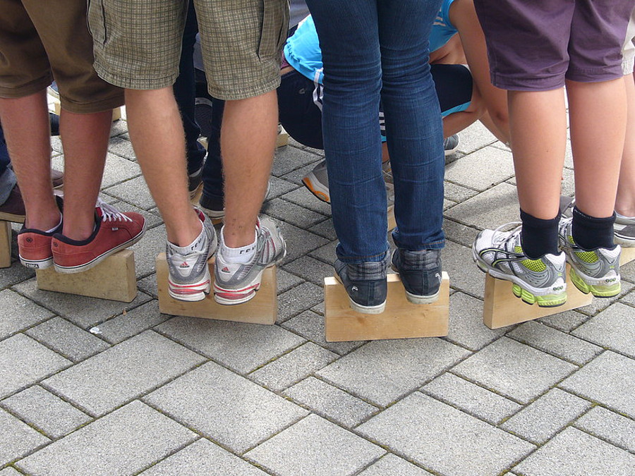 Kinder stehen auf Holzklötzen (Beine von hinten)
