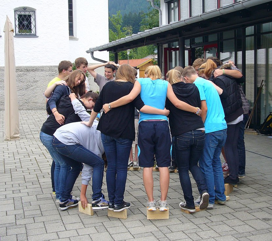 Schülergruppe balanciert auf Holzklötzen