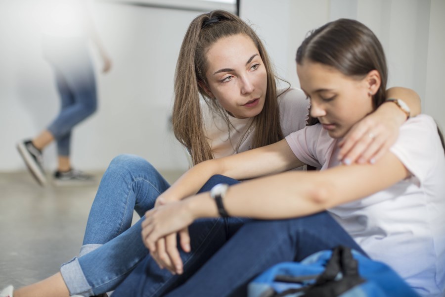 Schülerin tröstet Mitschülerin auf Schulflur