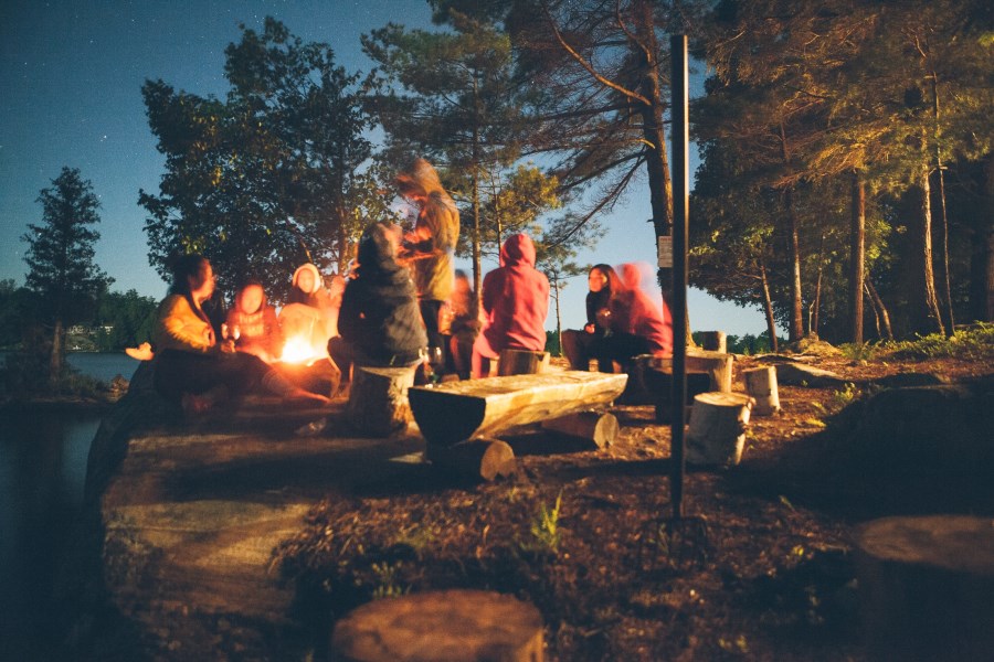 Jugendliche sitzen gemütlich um Lagerfeuer