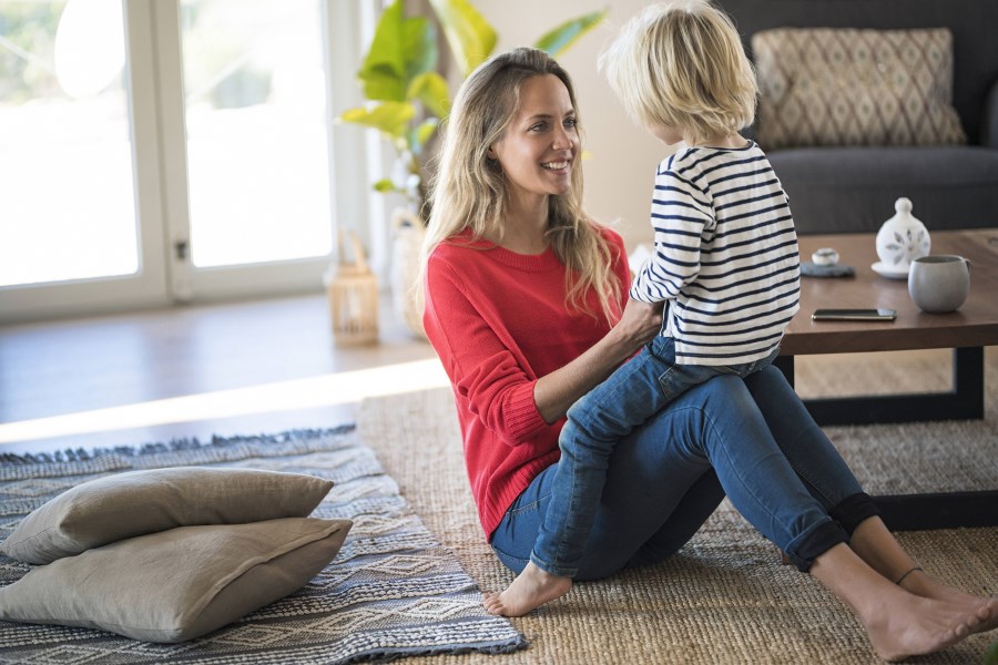 Mutter mit Kind auf den Knien im Wohnzimmer