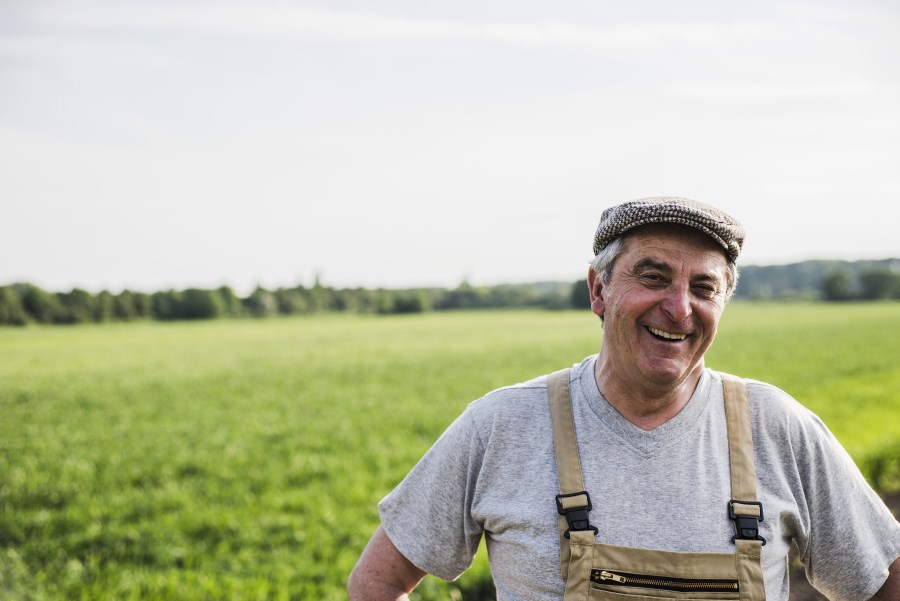 älterer Landwirt steht lachen in Feld