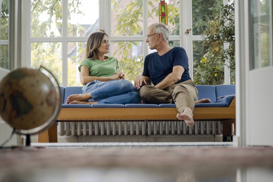 Paar sitzt auf Sofa am Fenster und unterhält sich