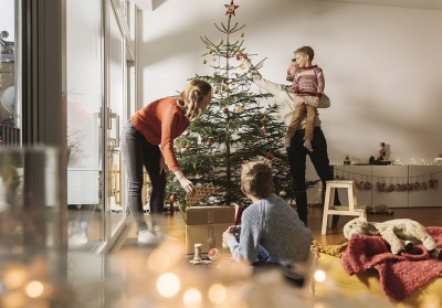 Mutter, Vater und zwei Kinder schmücken gemeinsam den Christbaum