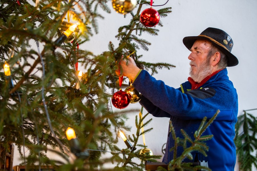 Mann schmückt Christbaum in Kirche