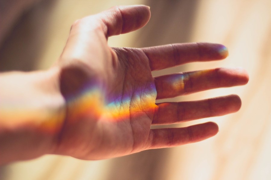 Hand, in der sich Regenbogen bildet