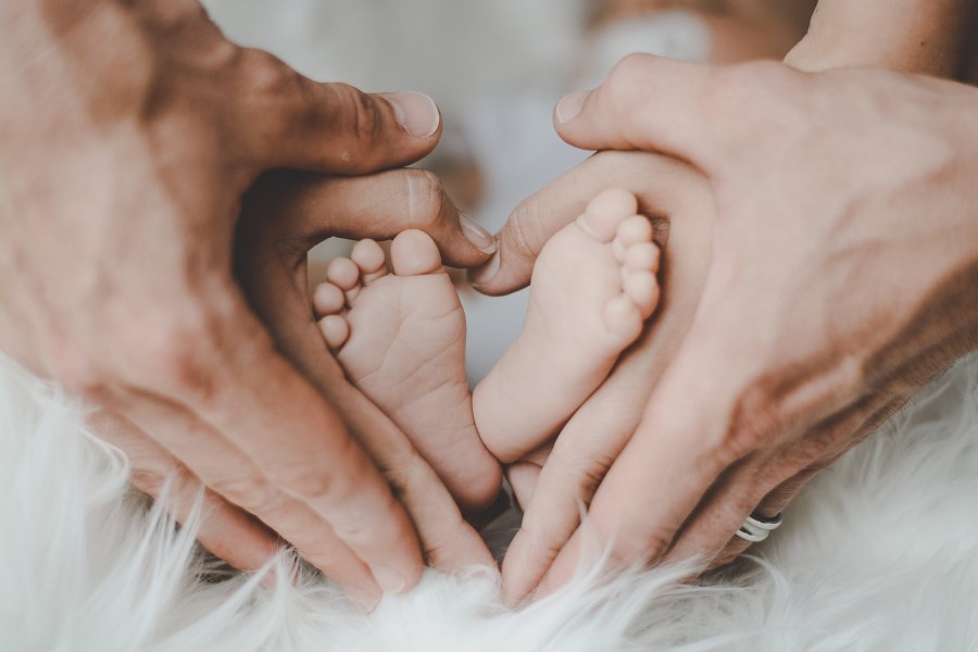 Babyfüße von Händen der Eltern gehalten