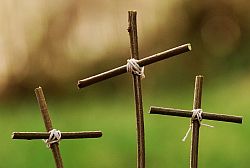 drei Kreuze aus Ästen vor grüner Natur