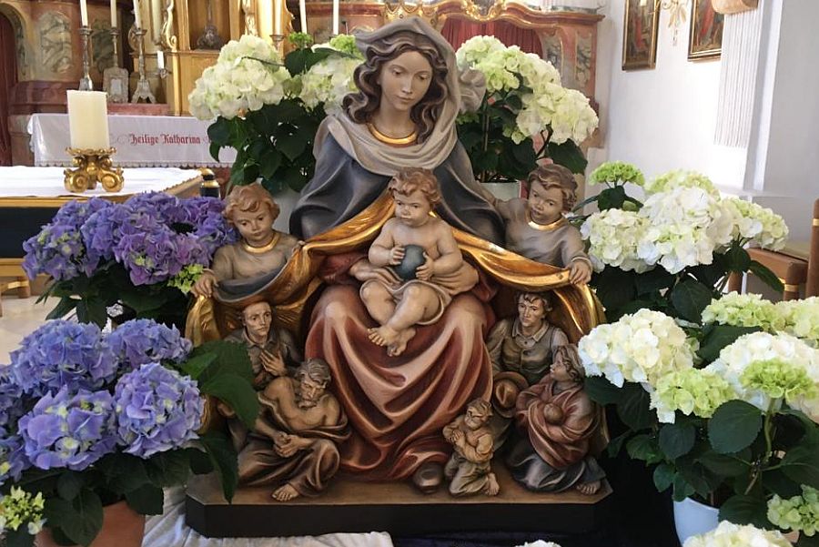 Schutzmantelmadonna in Kirche mit Blumen