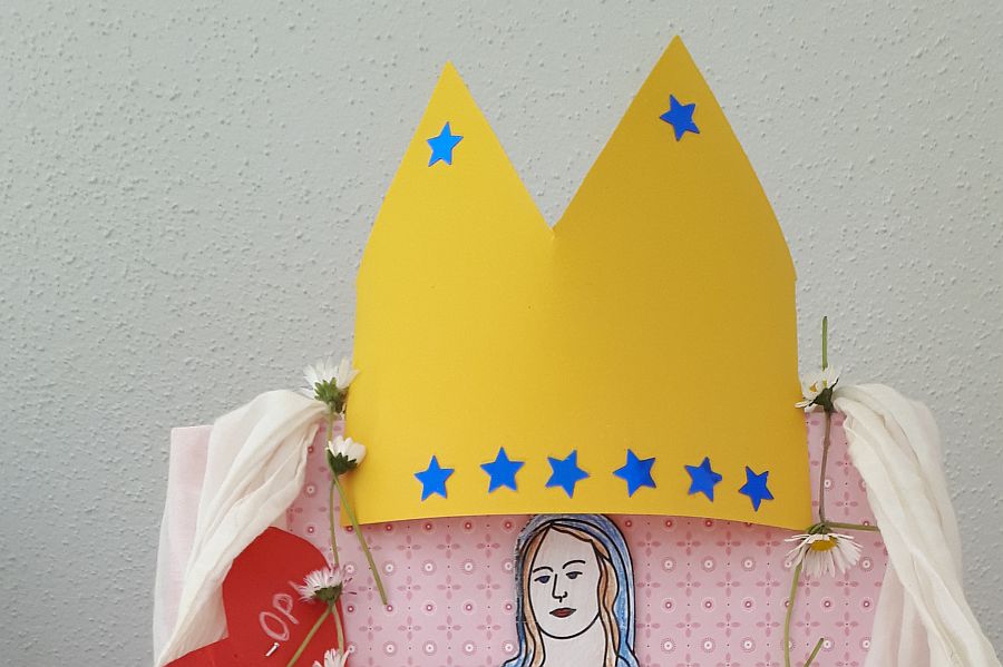 gelbe Krone mit blauen Sternen als Krönung von mit Mantel geschmückter Marienstatue
