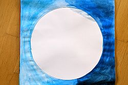 Blatt mit weißem Kreis in der Mitte, daneben eine Hälfte mit hellblauer und andere Hälfte mit dunkelblauer Wasserfaben ausgemalt