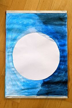 Blatt mit weißem Kreis in der Mitte, daneben eine Hälfte mit hellblauer und andere Hälfte mit dunkelblauer Wasserfaben ausgemalt