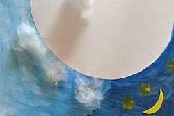 Wolken aus Watte auf einem blau bemalten Papier mit Mond und Sternen