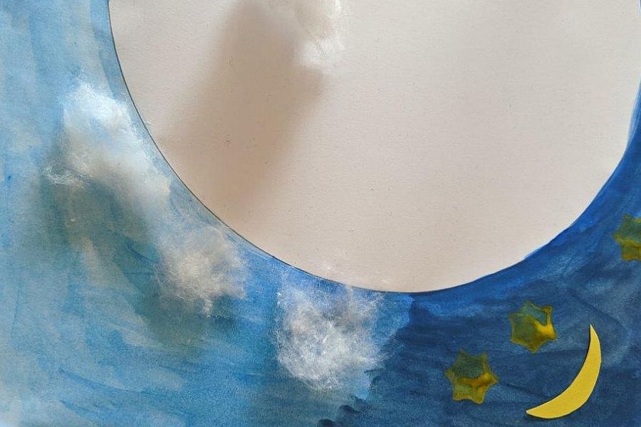 Wolken aus Watte auf einem blau bemalten Papier mit Mond und Sternen