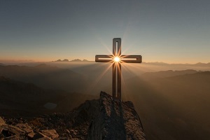 gipfelkreuz bei sonnenaufgang sonne scheint durch kreuzmitte