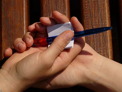 Hände halten Zettel und Stift