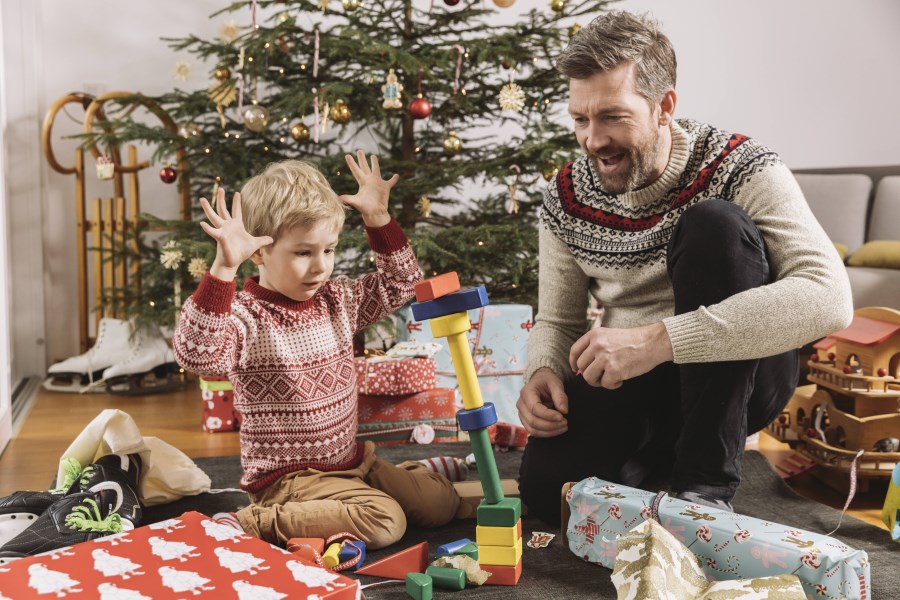 Vater spielt mit Sohn am Weihnachtsbaum