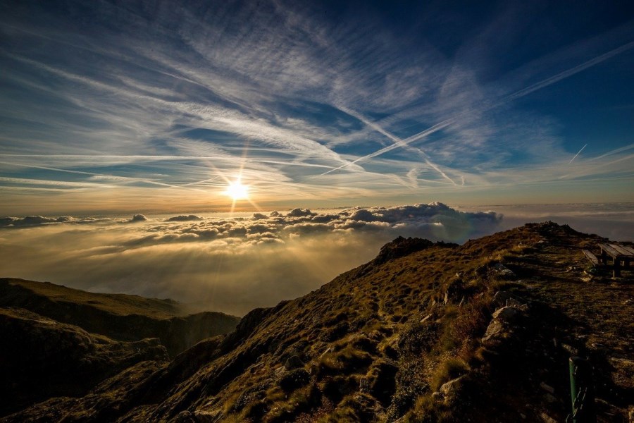 Sonne in Wolken über Bergen