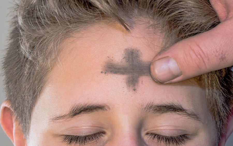 Finger zeichnen Jungen Aschenkreuz auf die Stirn