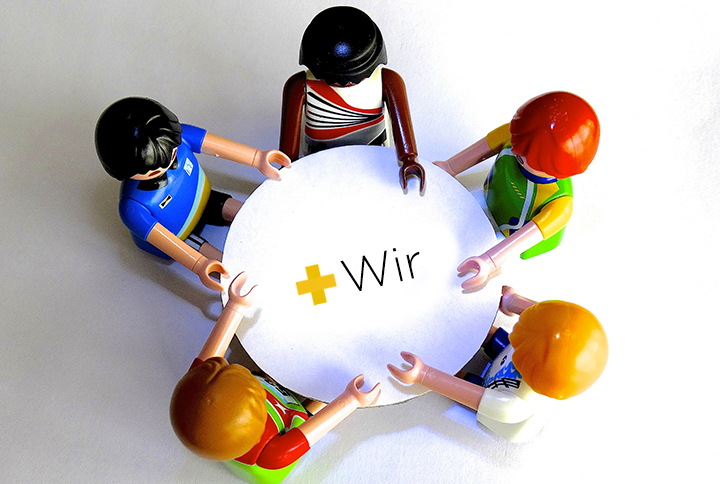 Playmobilfiguren um runden Tisch, Aufschrift Wir