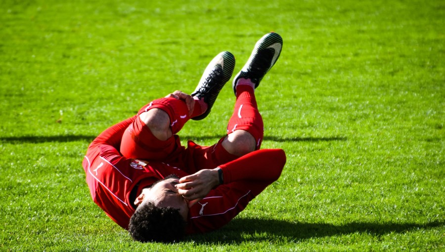 fußballer hält sich sein schienbein