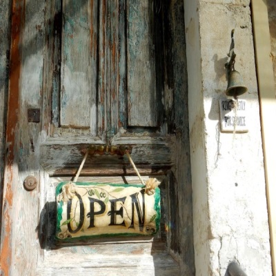 Eine Türe, an der ein Schild mit der Aufschrift OPEN hängt