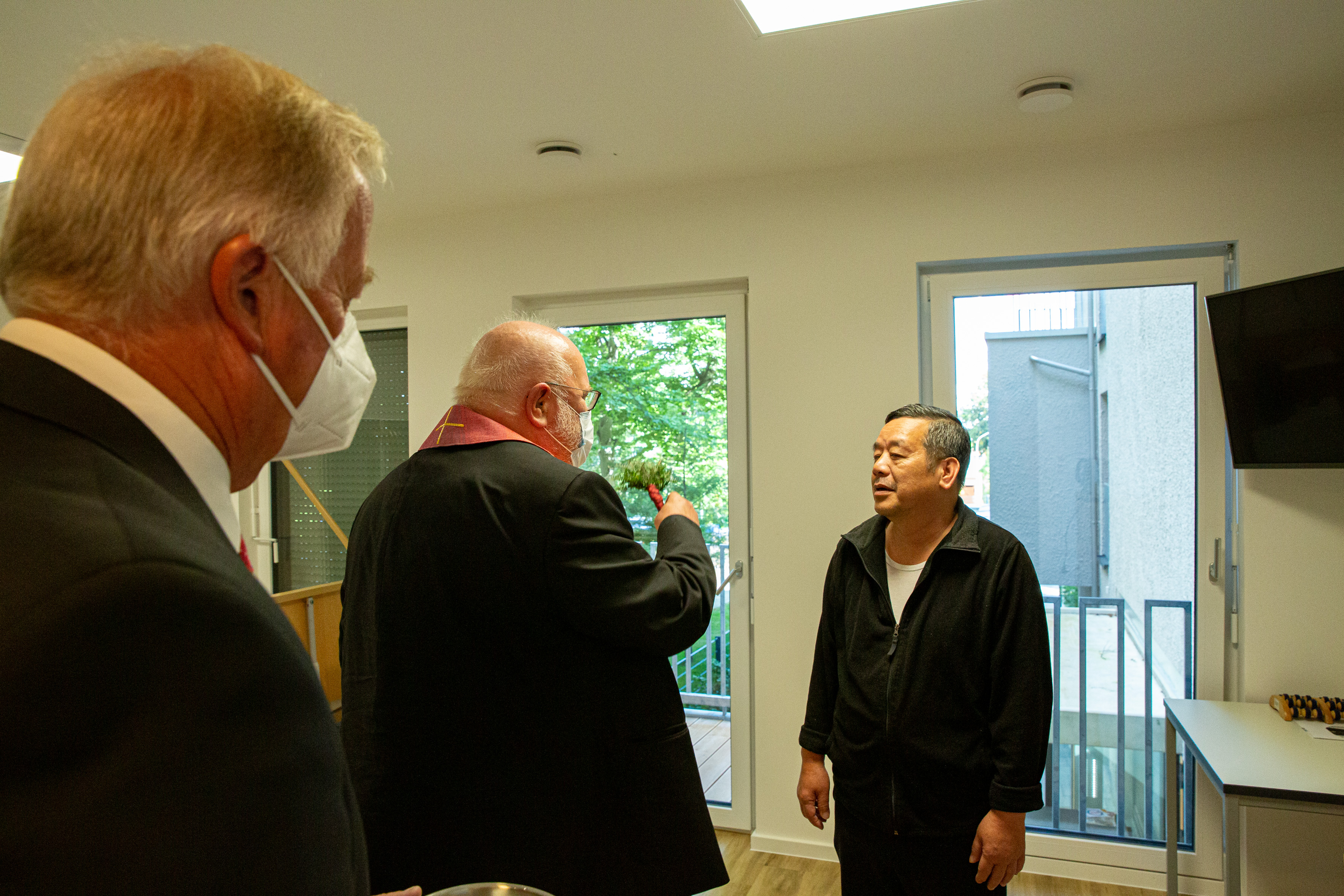 Auf dem Foto ist Kardinal Marx zu sehen, der in der Krankenwohnung einem obdachlosen Patienten begegnet.