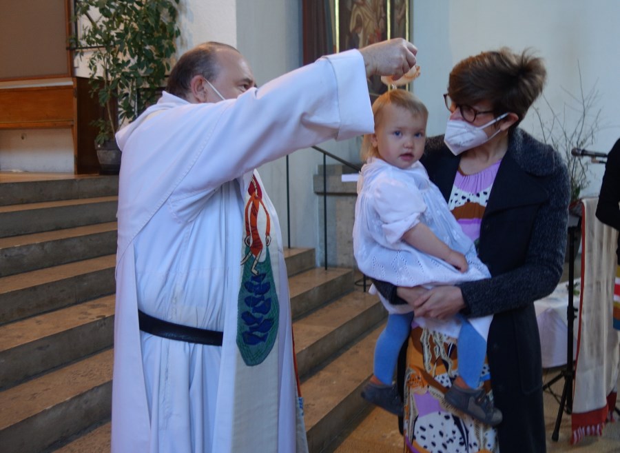 Ein Pfarrer tauft ein Kind.