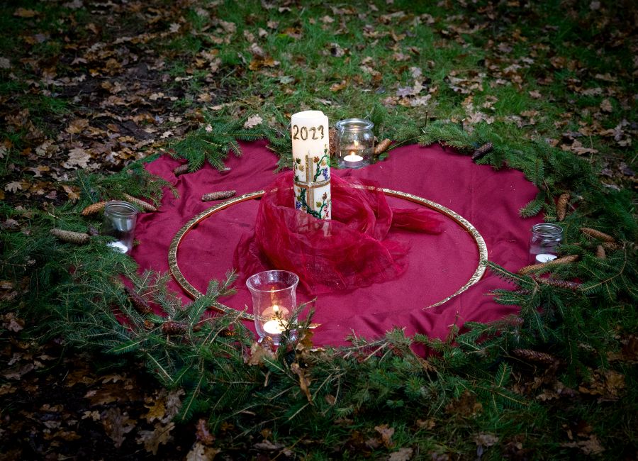 Brennende Kerze auf einem großen roten Tuch im Wald