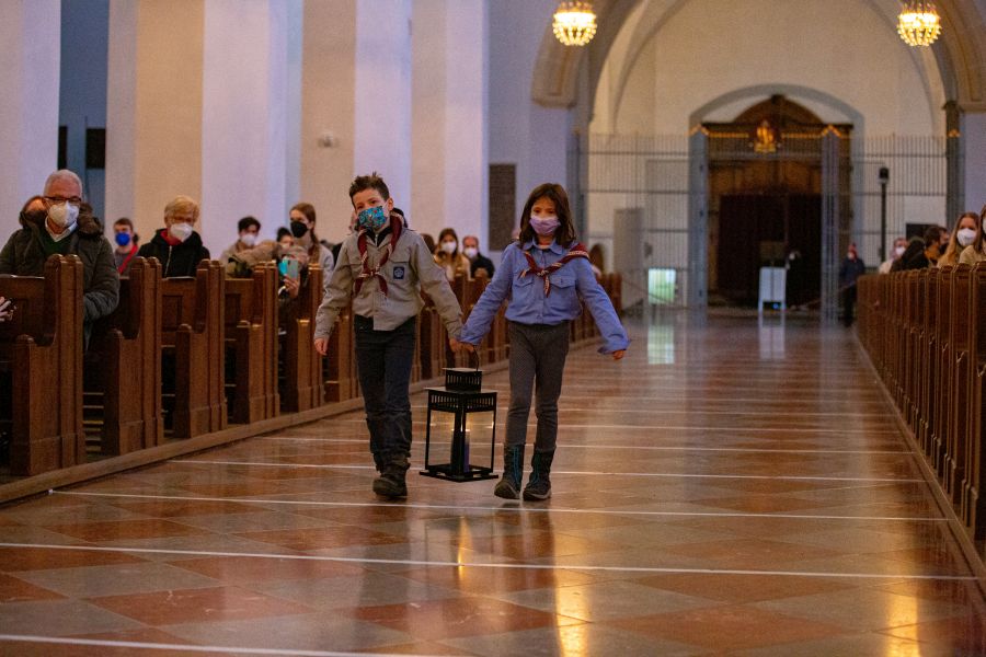 Ein Pfadfinderin und ein Pfadfinder tragen das Friedenslicht aus Betlehem in die Münchner Liebfrauenkirche