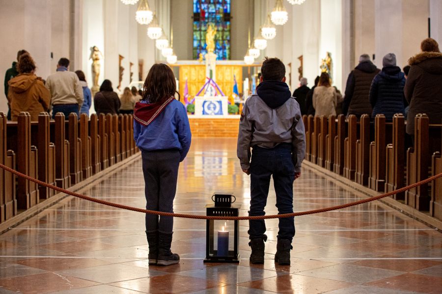 Eine Pfadfinderin und ein Pfadfinder warten auf ihren Einsatz im Gottesdienst zur Aussendung des Friedenslichts aus Betlehem in der Münchner Liebfrauenkirche