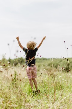 Kind beim Sprung auf der Wiese