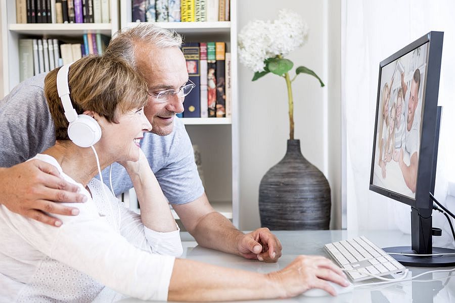 Mittelaltes Paar kommuniziert per Videokonferenz mit Familienangehörigen