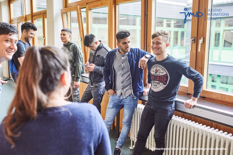 Auf dem Foto sind Schüler in der Aula zu sehen. Die Stimmung ist gut, alle lachen.