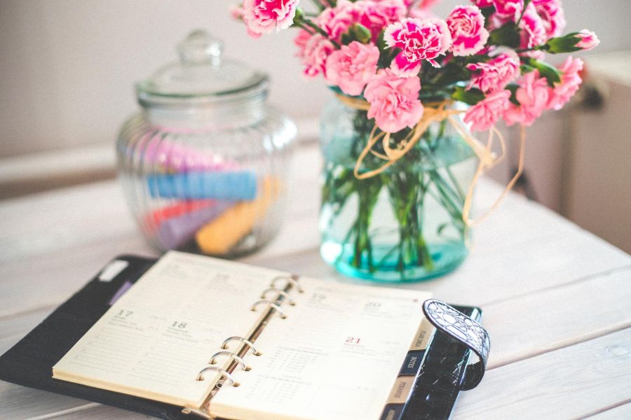 Kalender mit Stiften und Blumenvase