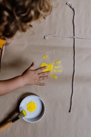 Kind malt Kreuz mit Fingerfarben