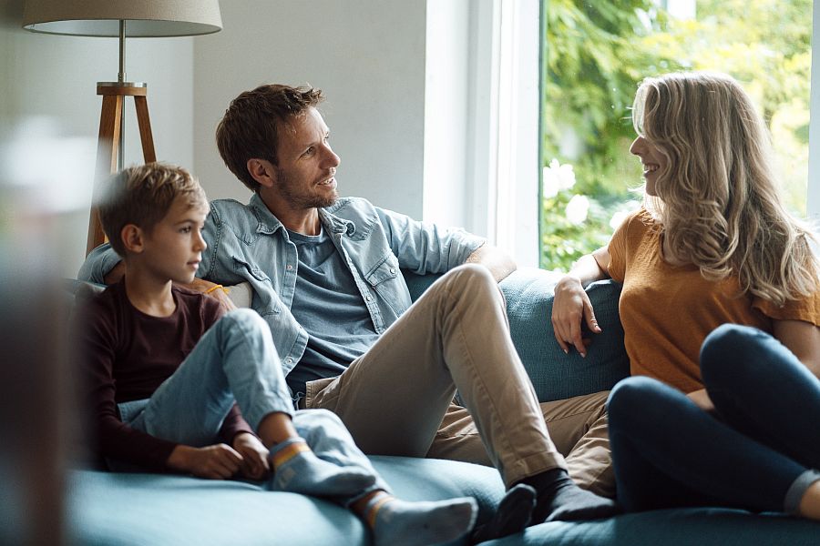 Vater, Mutter und Kinder sprechen gut gelaunt auf dem Sofa