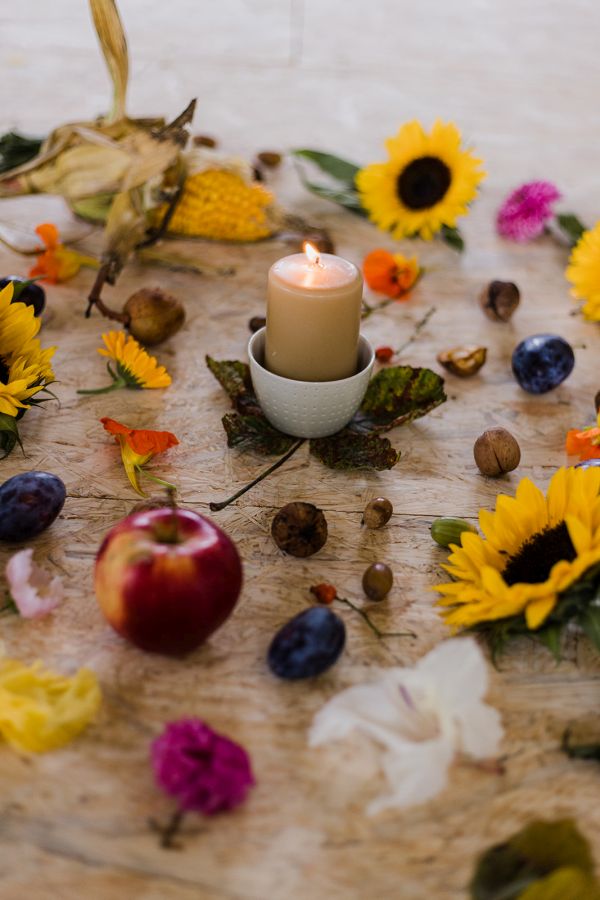 Kerze inmitten eines Kreises von Laub und Blumen