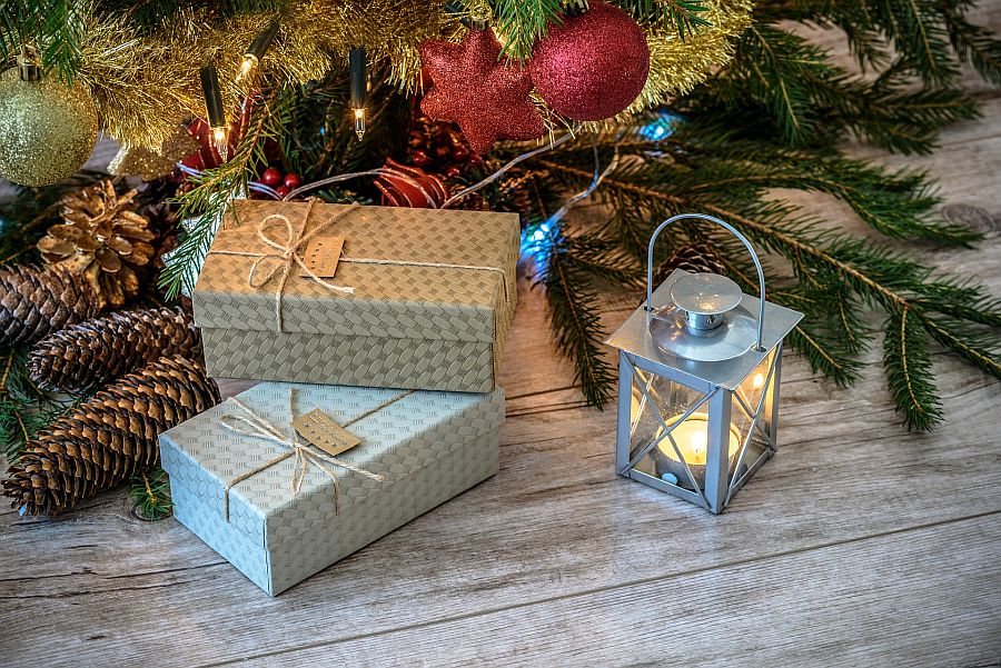 Weihnachtsgeschenke unter Baum mit Laterne und Tannenzapfen
