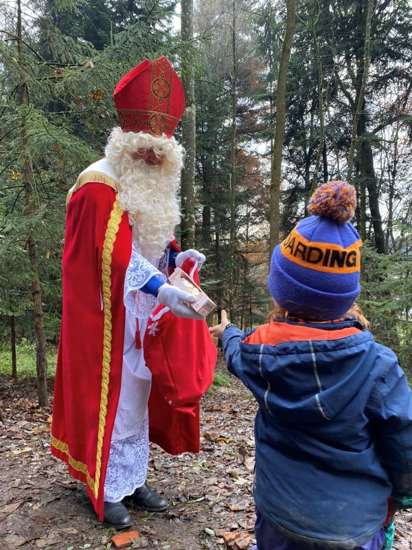 Der Nikolaus beschenkt im Waldkindergarten ein Kind mit einem Schokonikolaus